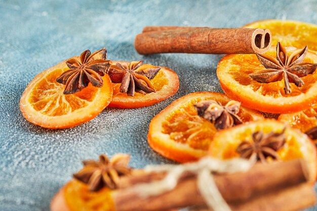 Slices of dried oranges or tangerines with anise and cinnamon, on a blue wall. Vegetarianism and healthy eating.