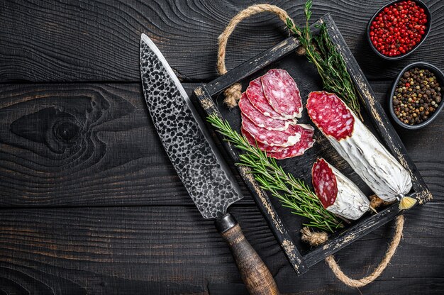 Slices of dry cured salchichon salami in a wooden tray.