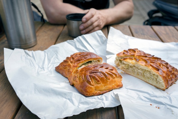 아름다운 빵 껍질을 가진 생선 조각과 양배추 파이 한 남자가 야외에서 신선한 공기를 마시며 아침 식사를 합니다