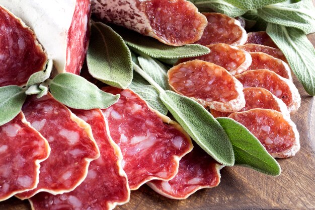 Slices of French cheese-dried salami with spices on wooden background