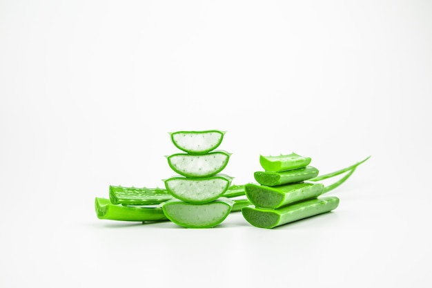 Slices of fresh aloe vera plant stacked on white background.