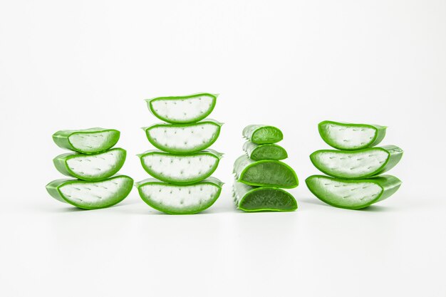 Slices of fresh aloe vera plant stacked on white background.