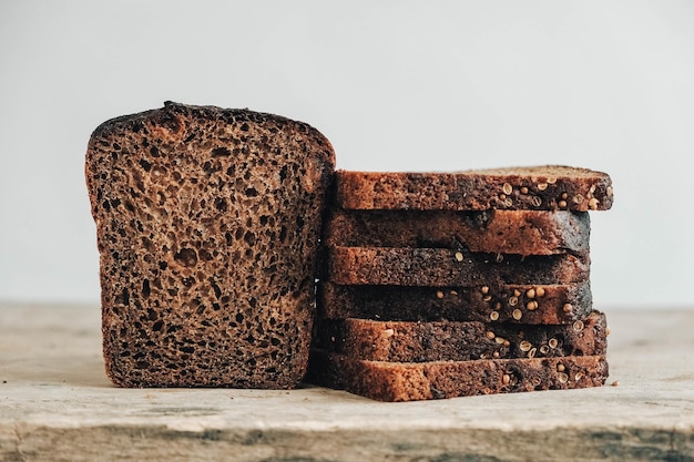 Slices of fresh brown bread with raisins on wooden background. Copy, empty space for text