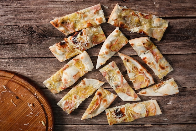 Slices of fresh hot pizza with ham and cheese on wooden table, flat lay. Italian national cuisine, fast food.