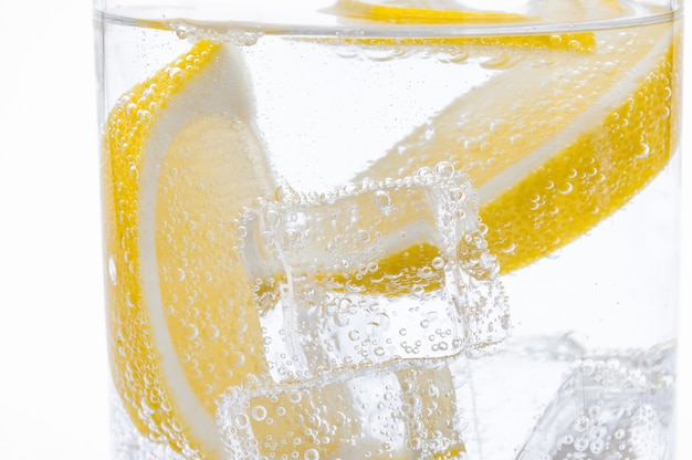 Slices of fresh juicy lemon drop into the cocktail with crystal clear water.