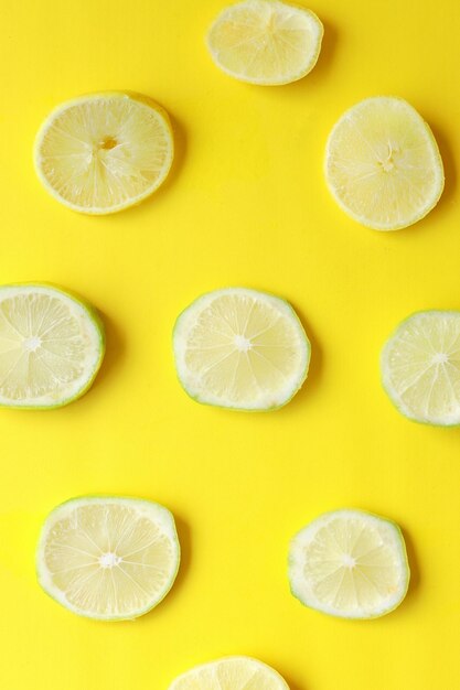 Photo slices of fresh juicy yellow lemons on yellow background texture background pattern