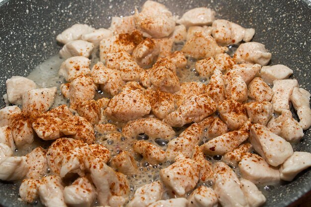 Foto fette di pollo fritto in padella processo di cottura da vicino