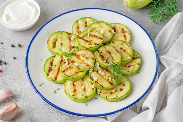 Slices of fried zucchini with garlic and fresh dill on a plate Vegetarian healthy dish