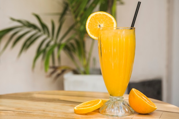 Photo slices of fruits near glass of drink with straw on table