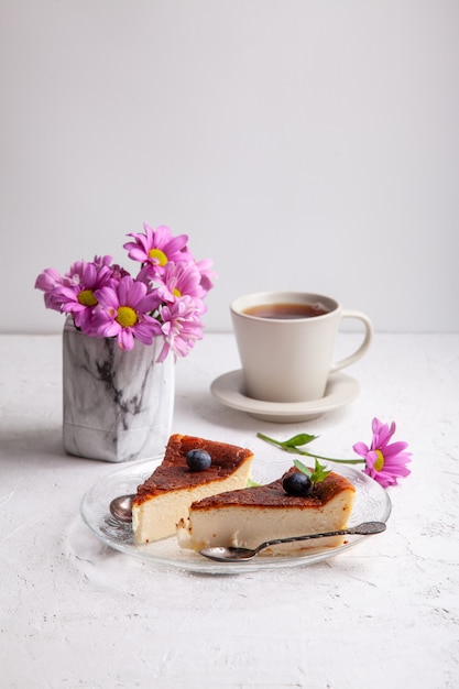 Slices of Homemade Basque burnt cheesecake on a plate with blueberries and mint leaves on light background