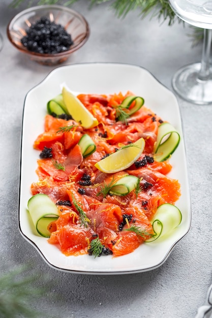 Slices of homemade smoked salmon fillet with dill, cucumber and lemon