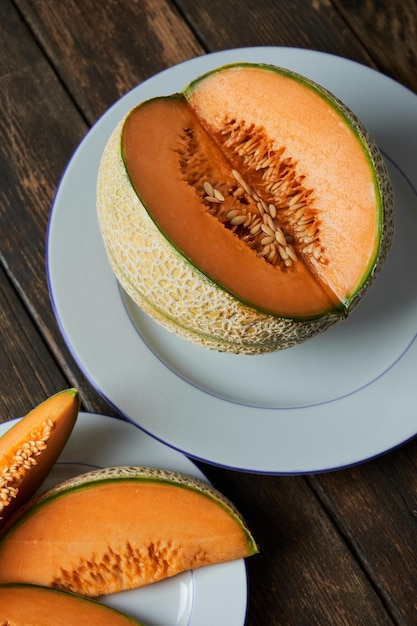 Foto fette di melone giapponese melone o cantalupo su tavola di legno piatto bianco sullo sfondo. vegano