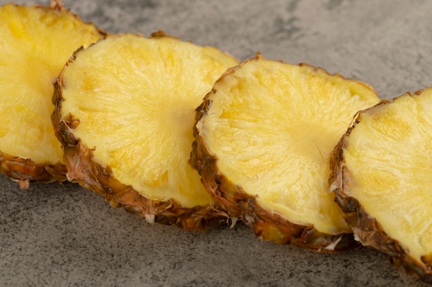 Кусочки сочного вкусного ананаса на каменной поверхности.