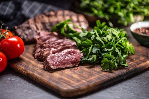 Slices of juicy grilled beef steak on a butcher plate.