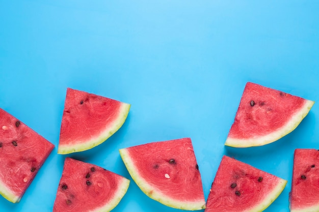 Slices of juicy red watermelon on blue. Top view, flat lay.