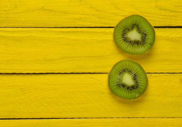 Photo slices of kiwi on a yellow wooden background. top view.