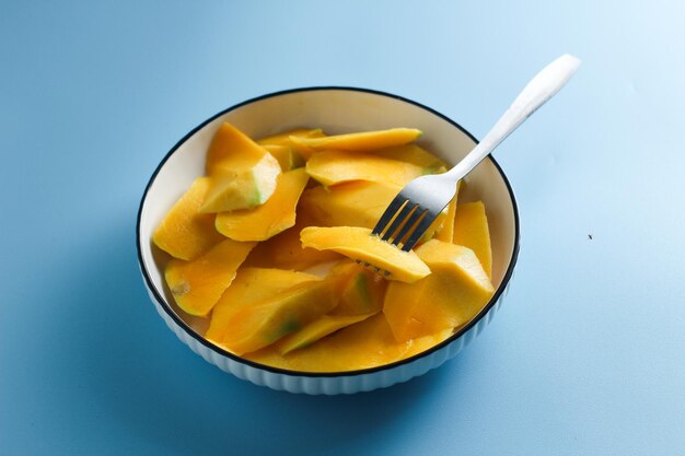 Slices of mango on a white salad plate on a light blue background