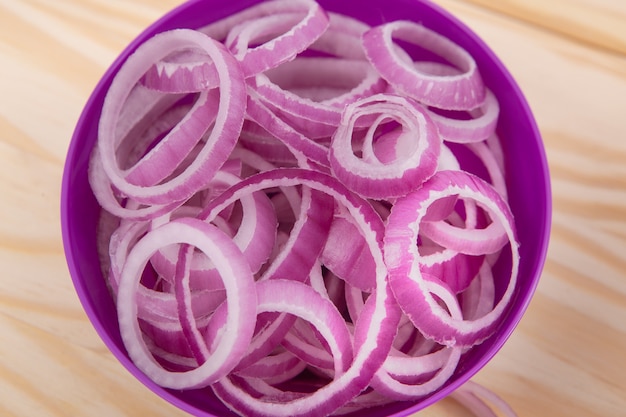 Slices ofonion. Onion in ceramic bowl on wooden background