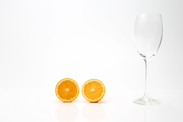 Slices of an orange and an empty glass on a white 
