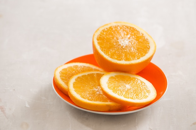 Slices of oranges in white dish on dark wooden table.