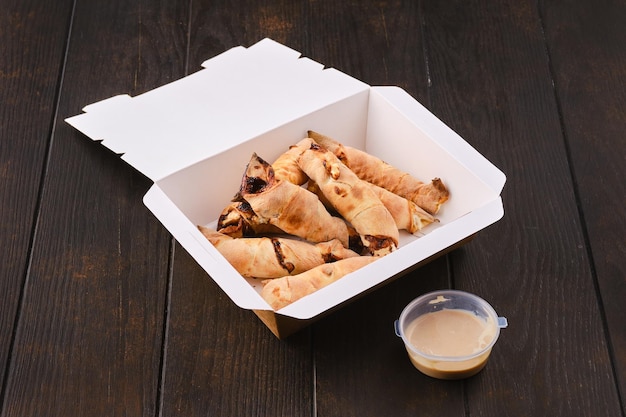 Slices of pear rolled in dough with caramel sauce in take away package