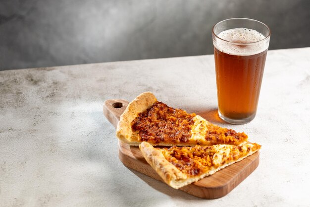 Photo slices of pizza with glass of beer on the table