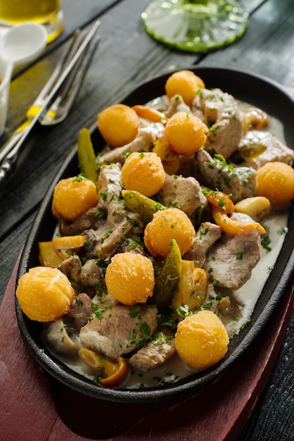Кусочки свинины и печени кролика с грибами в сметанном соусе с картофельными шариками.