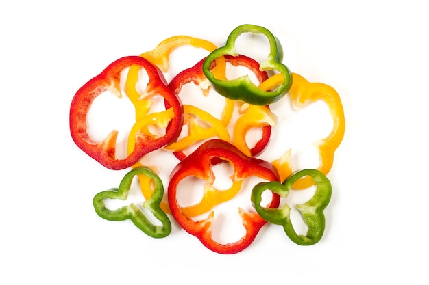 Slices of red, green and yellow peppers on a white background in a top view