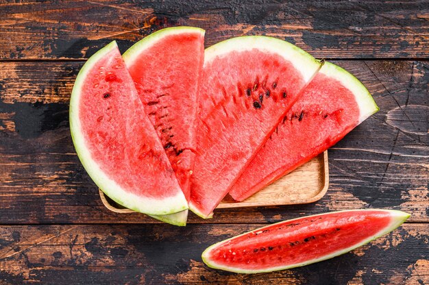 Slices of red striped watermelon. Dark Wooden background. Top view.