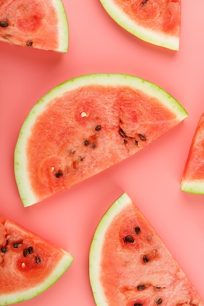 Slices of red watermelon on a pink  in the form. Minimal food  idea. Flat lay, top view.