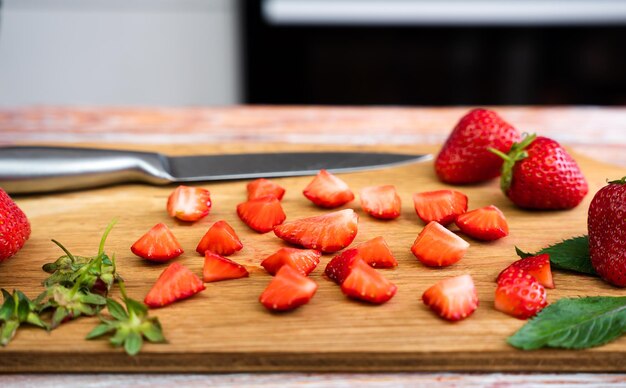 Photo slices of ripe strawberries on a cutting board in the kitchen lemonade with fresh strawberries