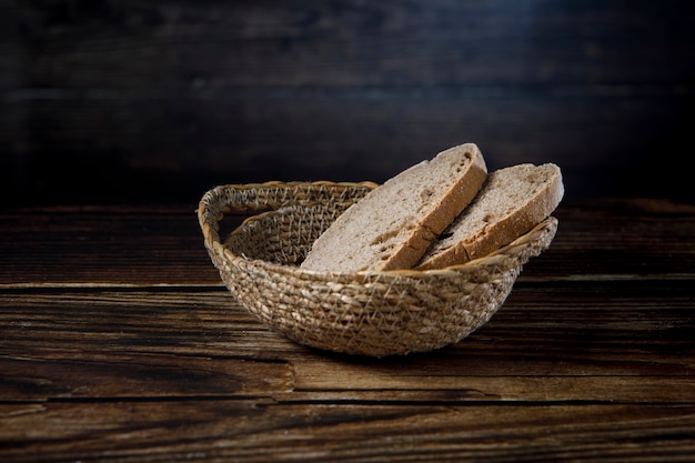 Slices of rustic bread in wicker bowl on a wood table