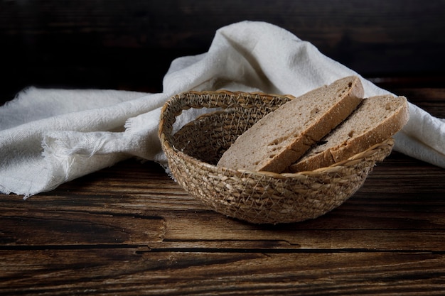 Slices of rustic bread in wicker bowl on a wood table