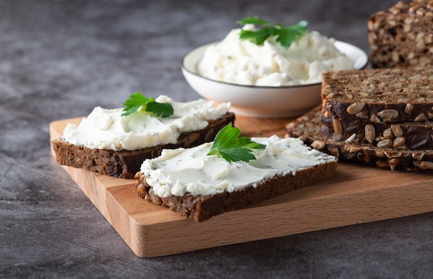 Slices of rye bread with cottage cheese on grey background