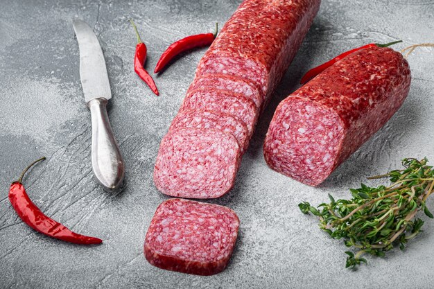 Slices of salami with vegetables set, on gray stone table