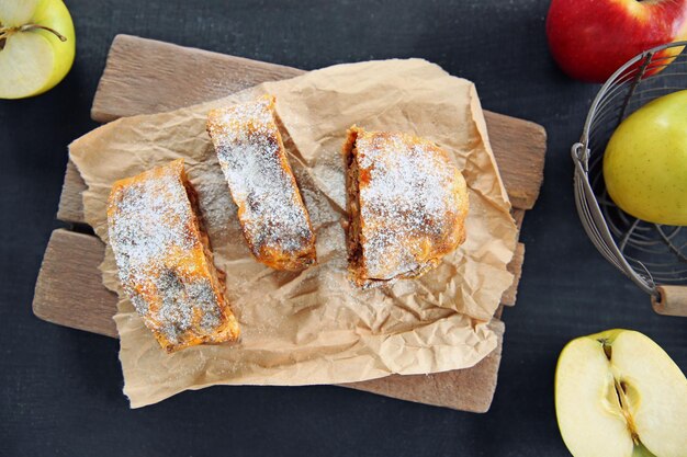 Photo slices of strudel with apples walnut and raisins on parchment