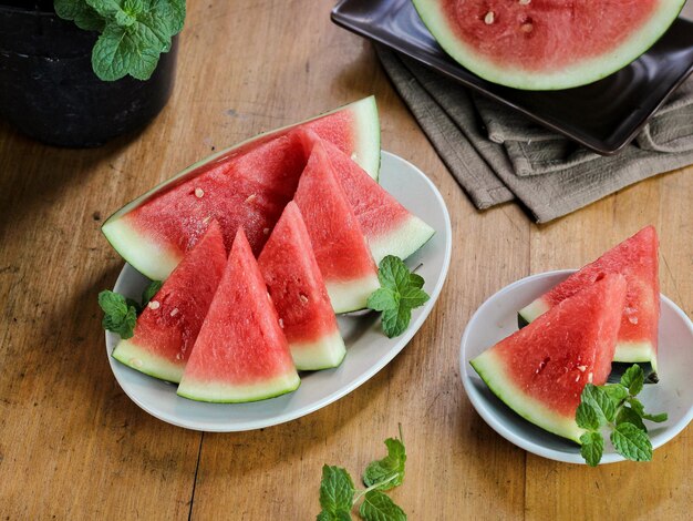 Slices of sweet watermelon on white plate with mint leaves on the wooden table