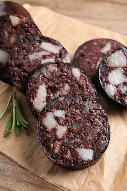 Slices of tasty blood sausage with rosemary on wooden table closeup