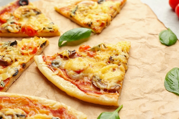 Slices of tasty pizza on parchment, closeup