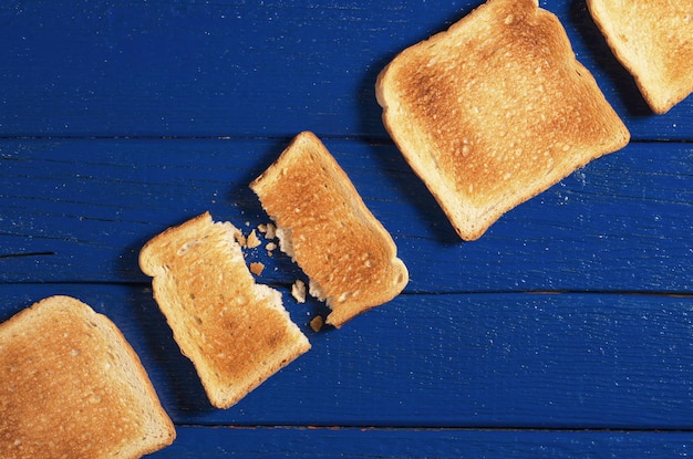 Fette di pane tostato sul tavolo di legno blu vicino alla vista dall'alto