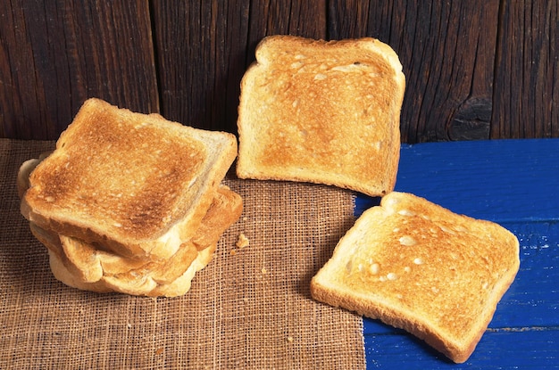 Slices of toasted bread on blue wooden table close up