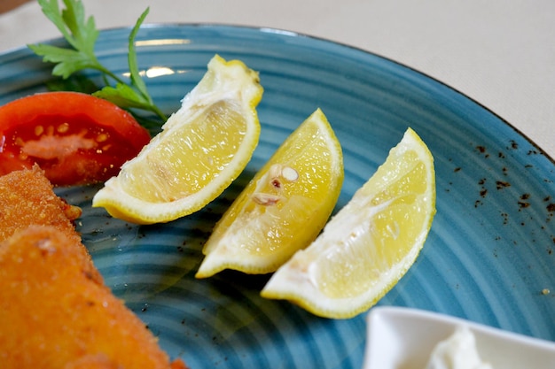 トマトとレモンのスライスとパン粉をまぶしたチーズを皿に盛ったもの