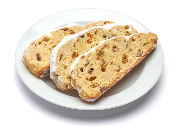 Slices of traditional christmas stollen cake with marzipan and dried fruit isolated on white ceramic...