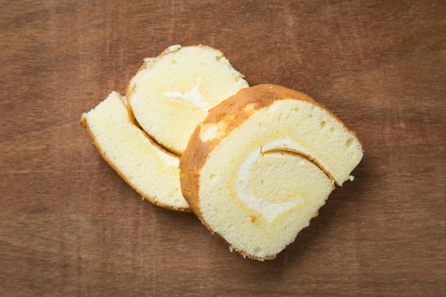 Slices of vanilla roll cake on wooden table.