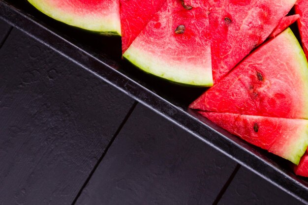 Slices of watermelon on dark boards Sliced watermelon in vintage baking sheet