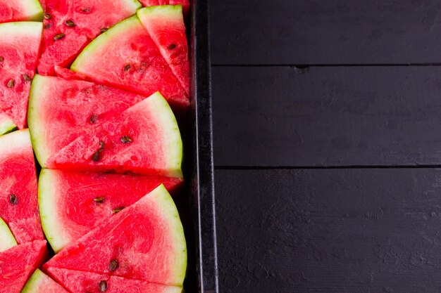 Slices of watermelon on dark boards Sliced watermelon in vintage baking sheet