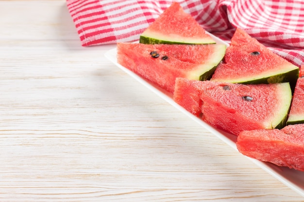 Slices of watermelon on the plate on white wooden background.