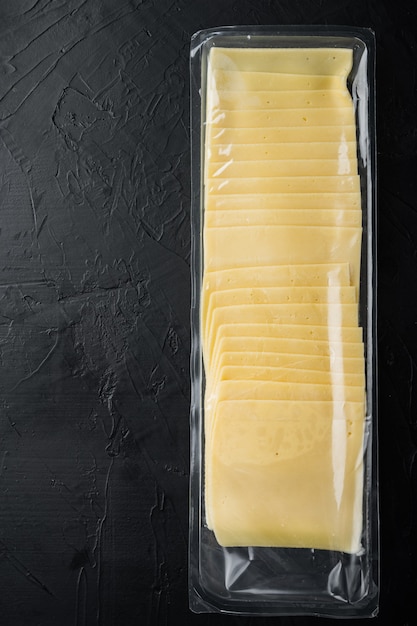 Slices of yellow cheese in sealed pack, on black table