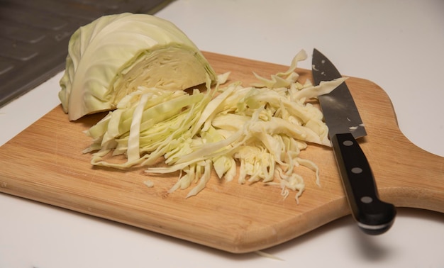 Slicing cabbage with knife on wooden board