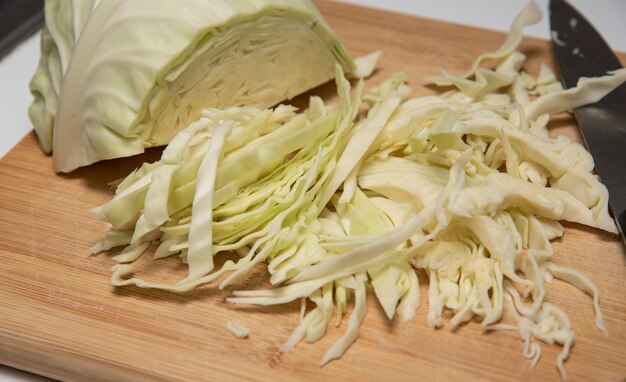 Slicing cabbage with knife on wooden board
